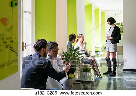 Stock Photograph - Young male and female business creatives having meetings in open plan office. Fotosearch