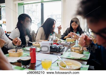 Stock Image - Young male and female business team sharing lunch in cafe. Fotosearch