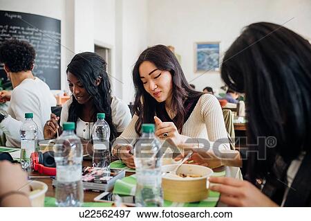 Stock Photo - Young male and female business team sharing lunch in cafe. Fotosearch