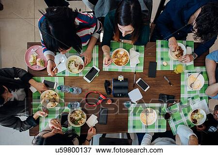 Young male and female business team sharing meal at cafe table, overhead view View Large Photo Image Stock Photo - Young male and female business team sharing meal at cafe table, overhead view. Fotosearch