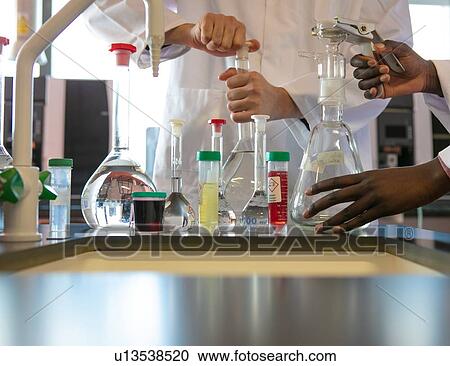 Stock Image - Young male and female scientists preparing experiment with sample bottles in laboratory, cropped. Fotosearch