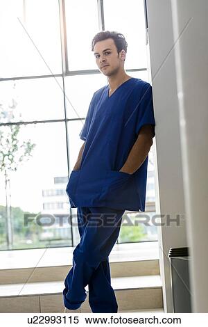 Stock Photography - Young male junior doctor in hospital corridor, portrait. Fotosearch