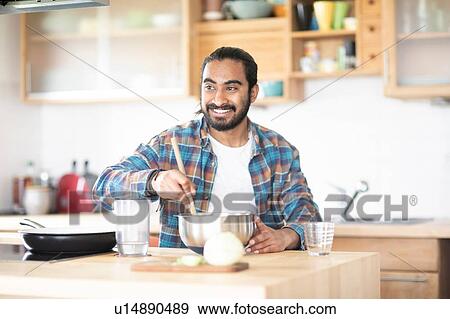 Young man at kitchen counter preparing food in mixing bowl View Large Photo Image Stock Photo - Young man at kitchen counter preparing food in mixing bowl. Fotosearch