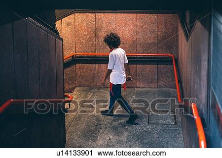 Stock Image - Young man descending stairway. Fotosearch
