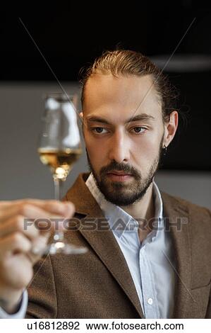 Stock Image - Young man examining glass of wine. Fotosearch