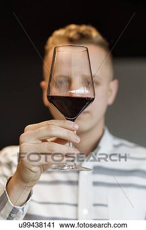 Stock Image - Young man examining glass of wine. Fotosearch