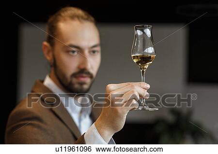 Stock Photograph - Young man examining glass of wine. Fotosearch