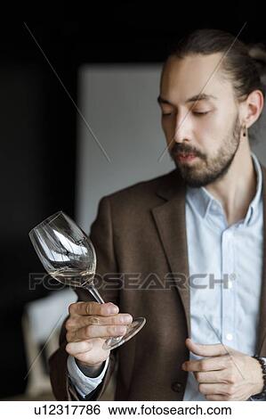 Stock Photograph - Young man examining glass of wine. Fotosearch