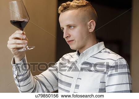 Stock Photograph - Young man examining glass of wine. Fotosearch