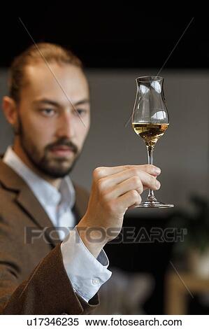 Stock Photography - Young man examining glass of wine. Fotosearch