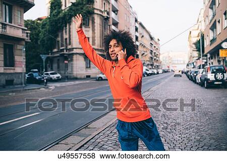 Young man hailing cab in city, Milano, Lombardia, Italy View Large Photo Image Stock Photo - Young man hailing cab in city, Milano, Lombardia, Italy. Fotosearch
