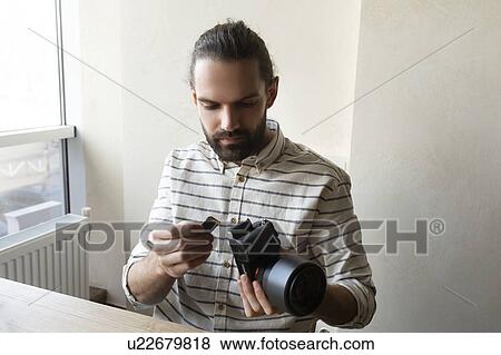 Stock Photo - Young man holding camera and SD card. Fotosearch