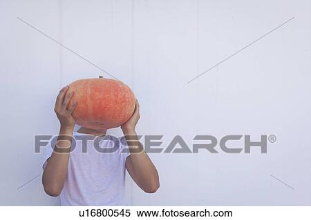 Stock Photography - Young man holding pumpkin over his face. Fotosearch