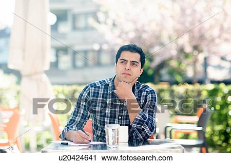 Stock Image - Young man in deep thought at cafe. Fotosearch