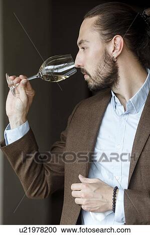 Stock Image - Young man smelling wine in glass at tasting. Fotosearch