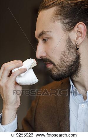 Stock Image - Young man smelling wine on cork at tasting. Fotosearch