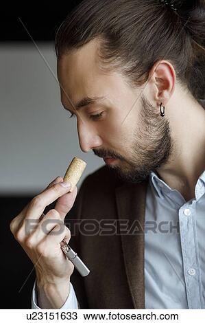 Young man smelling wine on cork at tasting View Large Photo Image Stock Image - Young man smelling wine on cork at tasting. Fotosearch