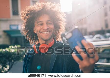 Stock Image - Young man taking selfie in city, Milano, Lombardia, Italy. Fotosearch