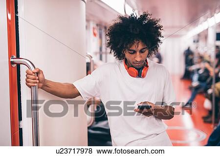 Young man using smartphone on train View Large Photo Image Stock Photo - Young man using smartphone on train. Fotosearch
