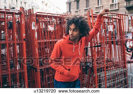 Stock Image - Young man waiting beside steel frames. Fotosearch