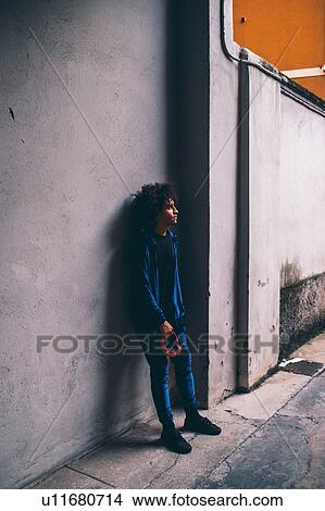 Young man waiting in front of concrete wall View Large Photo Image Picture - Young man waiting in front of concrete wall. Fotosearch