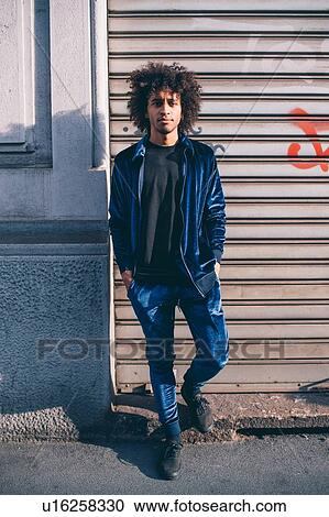 Young man waiting in front of shutters View Large Photo Image Stock Image - Young man waiting in front of shutters. Fotosearch