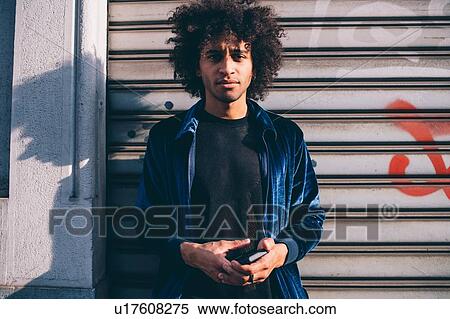 Stock Photography - Young man waiting in front of shutters. Fotosearch