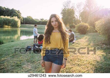 Stock Image - Young woman and friends by lake. Fotosearch