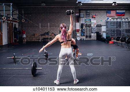 Young woman and man training, lifting dumbbells in gym View Large Photo Image Stock Image - Young woman and man training, lifting dumbbells in gym. Fotosearch