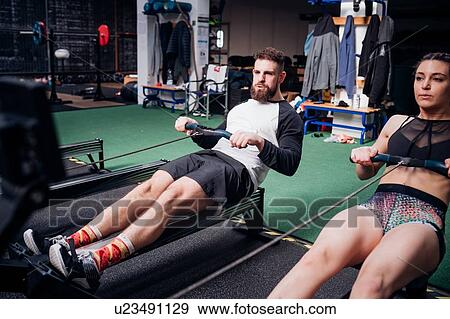 Young woman and man training on rowing machines together in gym View Large Photo Image Stock Photo - Young woman and man training on rowing machines together in gym. Fotosearch