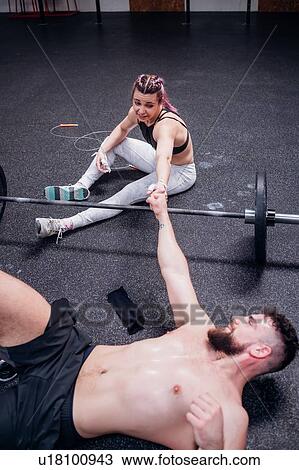 Stock Image - Young woman and man training together, fist bumping each other in gym. Fotosearch