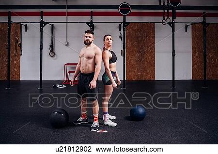 Young woman and man training together, back to back portrait in gym View Large Photo Image Stock Image - Young woman and man training together, back to back portrait in gym. Fotosearch