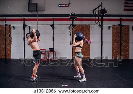 Young woman and man training together, carrying atlas ball on shoulders in gym View Large Photo Image Stock Photography - Young woman and man training together, carrying atlas ball on shoulders in gym. Fotosearch