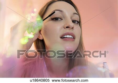 Stock Photography - Young woman applying mascara. Fotosearch
