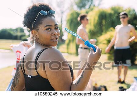Young woman blowing bubbles in park View Large Photo Image Stock Photography - Young woman blowing bubbles in park. Fotosearch