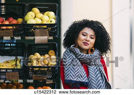 Stock Image - Young woman by crates of fruit. Fotosearch