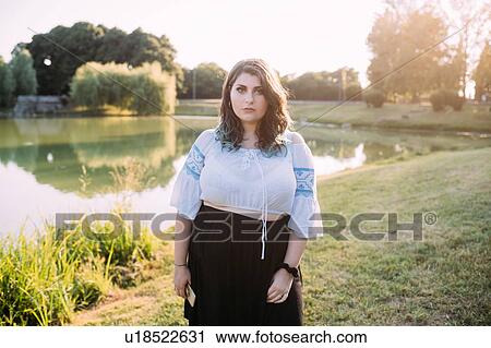 Stock Image - Young woman by lake. Fotosearch