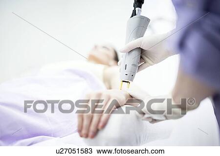 Stock Image - Young woman getting laser hair removal treatment on wrist, close-up.. Fotosearch