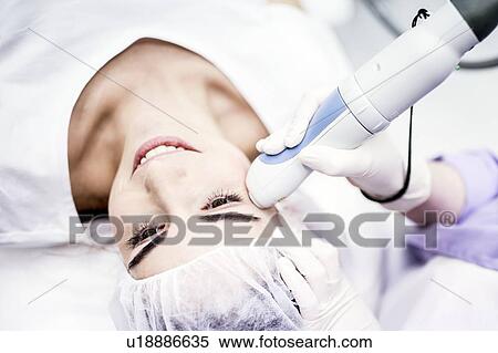 Stock Photography - Young woman having laser peeling treatment, close-up. This treatment smooths and rejuvenates the skin.. Fotosearch