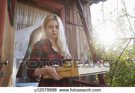 Stock Photo - Young woman holding crate of apples. Fotosearch