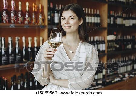 Young woman holding glass of white wine View Large Photo Image Stock Photo - Young woman holding glass of white wine. Fotosearch
