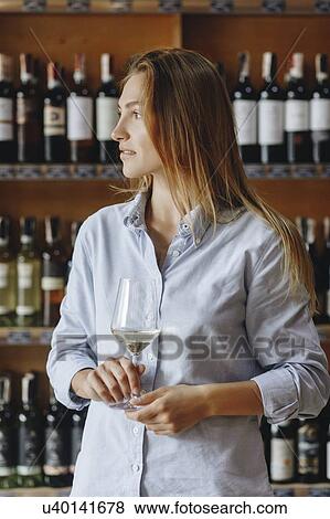 Young woman holding glass of white wine View Large Photo Image Stock Photo - Young woman holding glass of white wine. Fotosearch