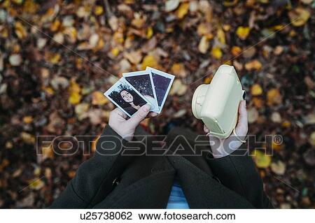Young woman holding instant photos and camera in autumn park, overhead view View Large Photo Image Stock Image - Young woman holding instant photos and camera in autumn park, overhead view. Fotosearch
