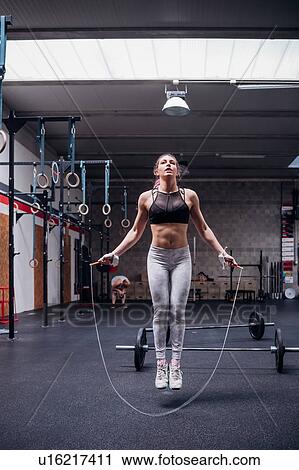 Young woman in gym skipping, full length View Large Photo Image Stock Image - Young woman in gym skipping, full length. Fotosearch