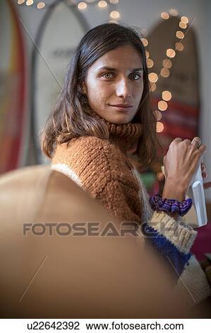 Young woman in knit sweater relaxing on living room sofa looking over her shoulder, portrait View Large Photo Image Stock Image - Young woman in knit sweater relaxing on living room sofa looking over her shoulder, portrait. Fotosearch