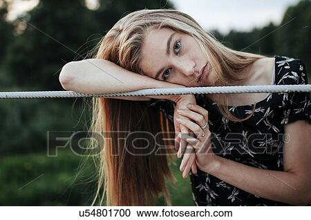 Young woman leaning on metal fence View Large Photo Image Stock Image - Young woman leaning on metal fence. Fotosearch