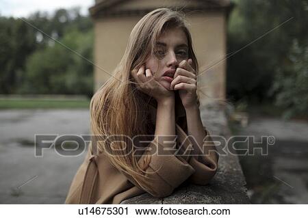 Stock Image - Young woman leaning on wall. Fotosearch
