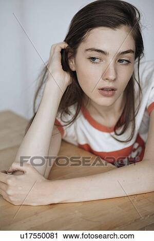 Young woman leaning on wooden table View Large Photo Image Stock Image - Young woman leaning on wooden table. Fotosearch