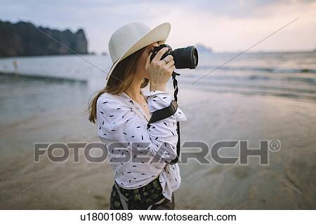 Stock Photo - Young woman photographing on beach in Krabi, Thailand. Fotosearch