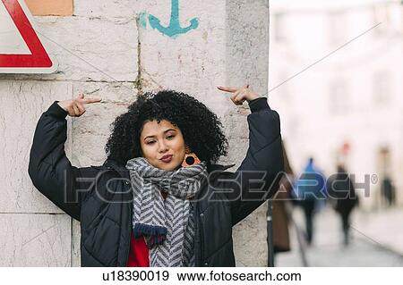 Stock Photo - Young woman posing under arrow on wall. Fotosearch